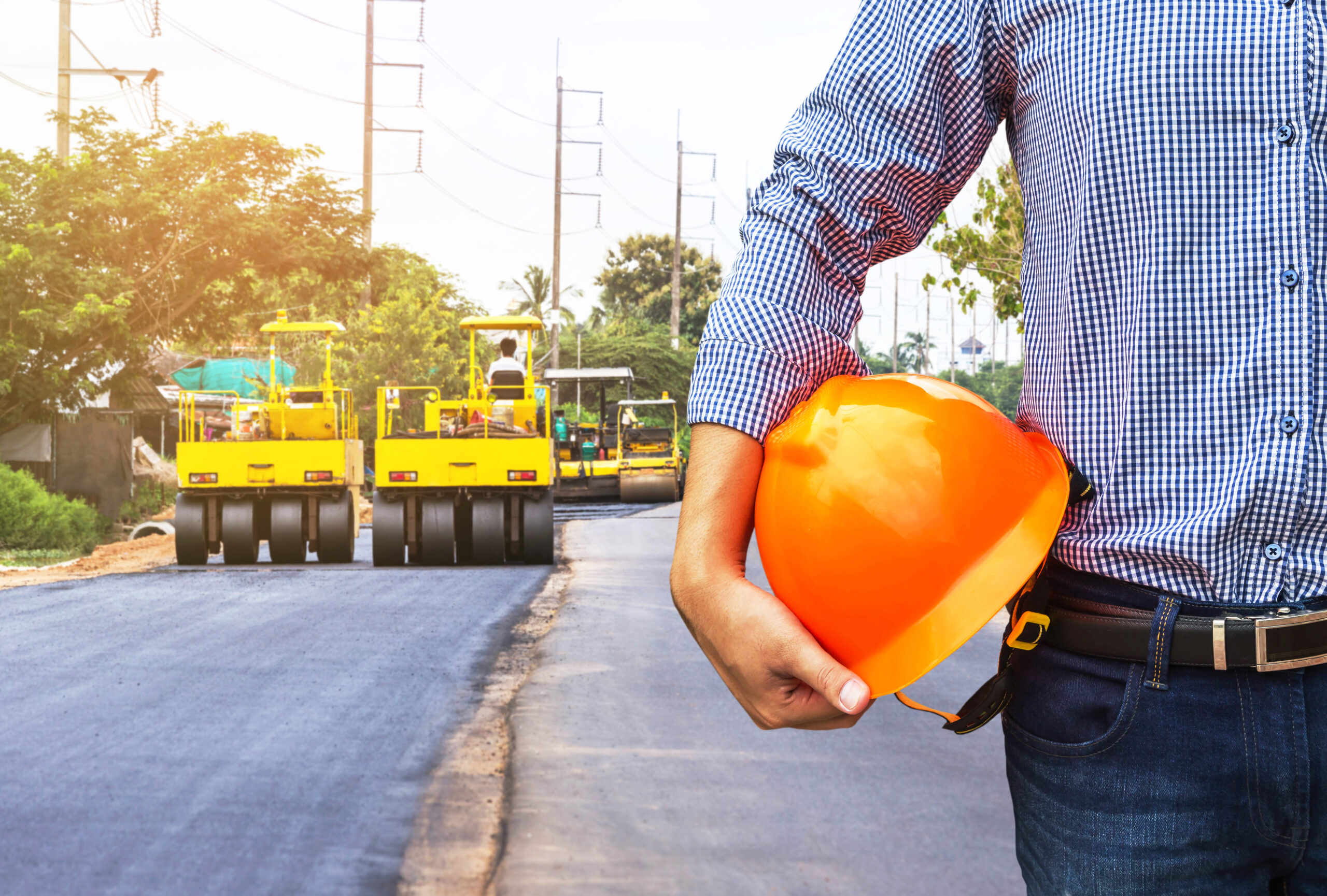 Engineer,Holding,Safety,Helmet,At,Road,Construction,Site,With,Roller Asphalt or Concrete?