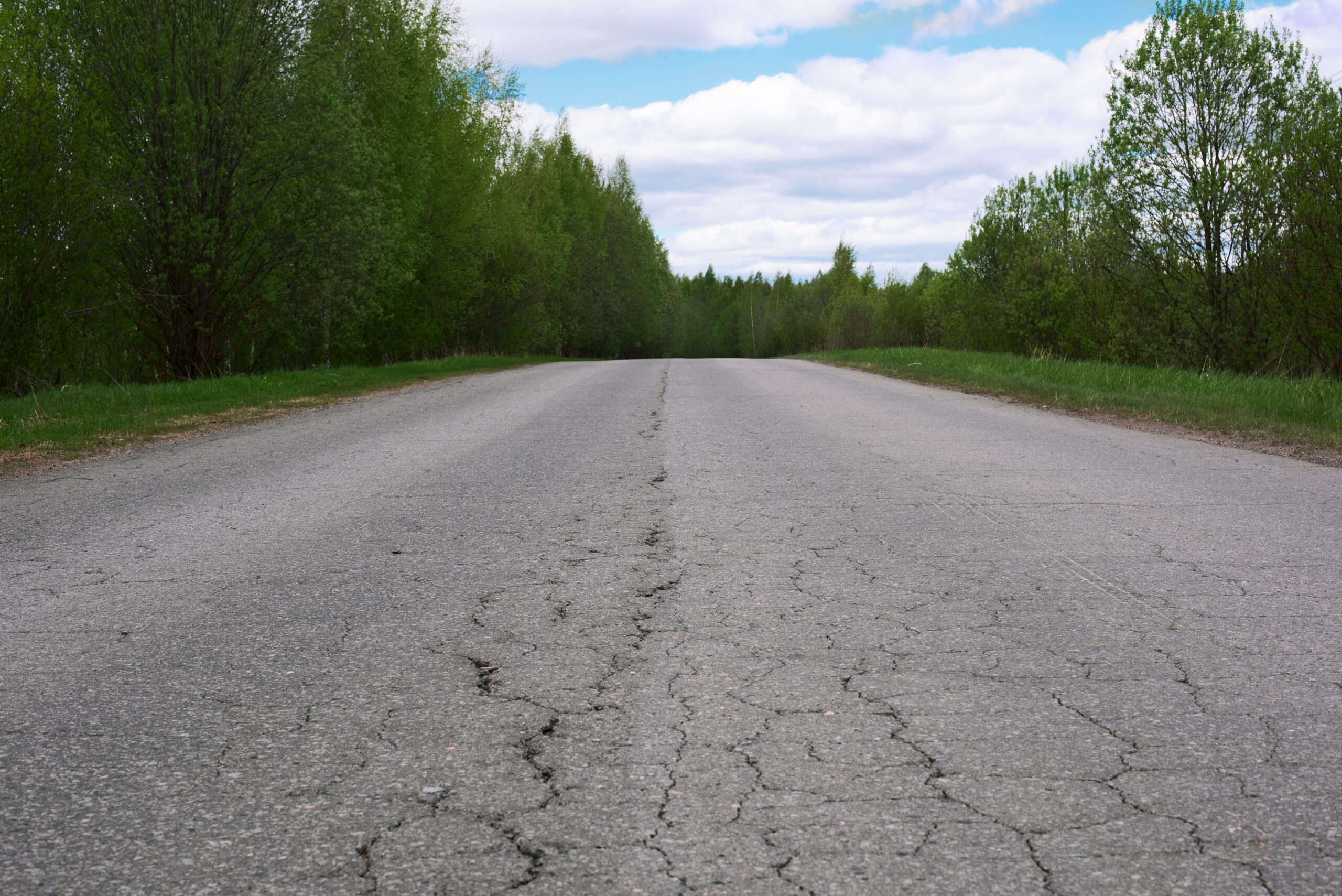 Landscape,With,A,Road,Damaged,By,Asphalt,,Trees,And,Sky